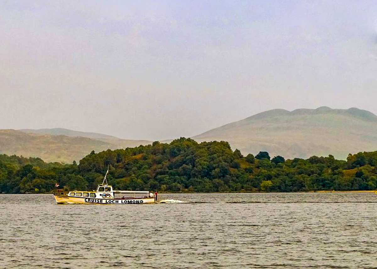 Passenger boat cruising on Loch Lomond with islands and hills in the background