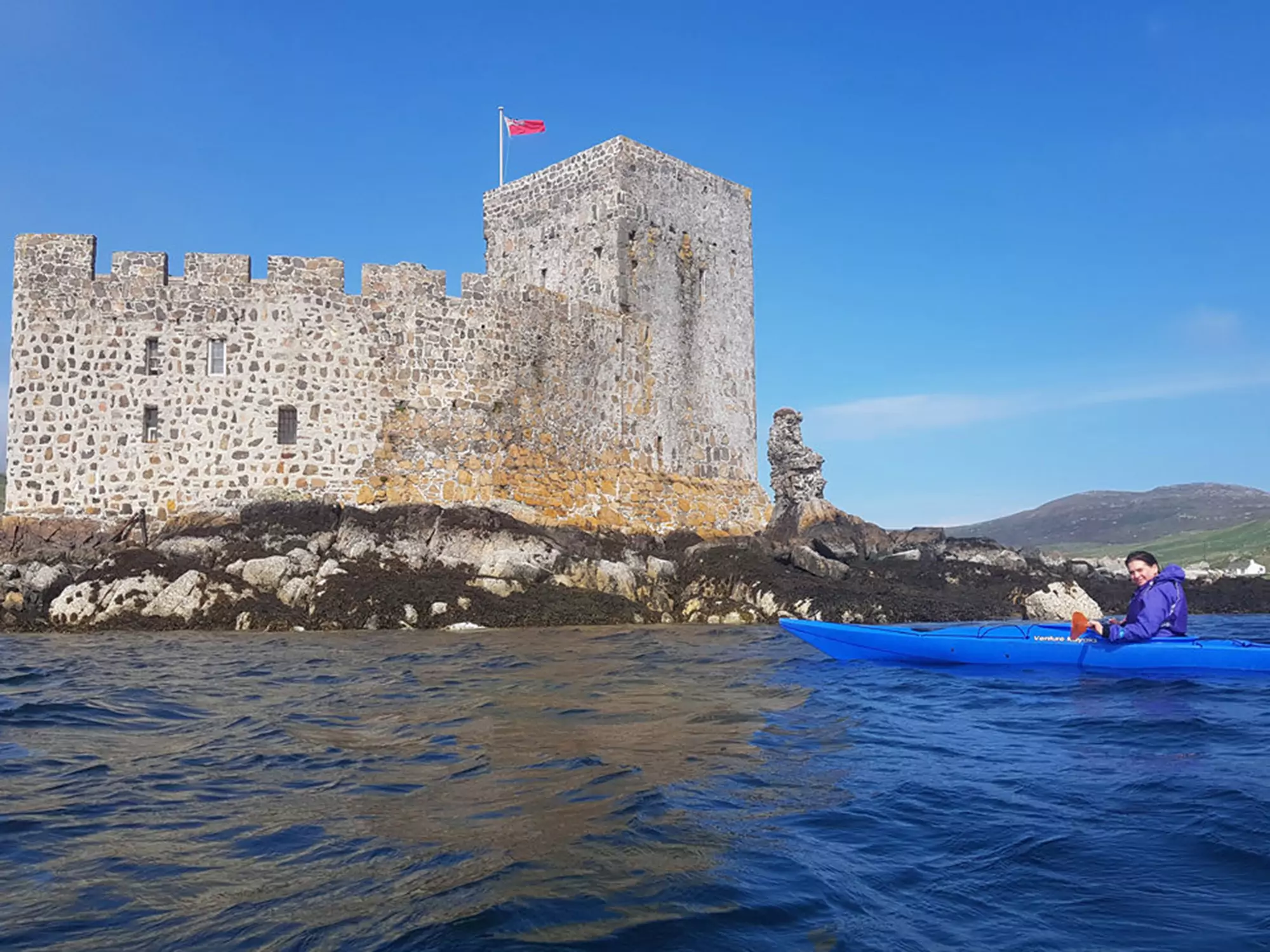 Kayaker near historic stone castle on the Isle of Barra